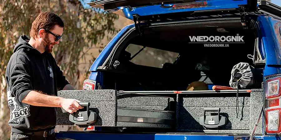 Радість від ідеального порядку легкий доступ до всього спорядження Щасливий чоловік з легкістю відкриває повністю завантажену висувну шухляду в своєму позашляховику, демонструючи зручність та радість від організованого простору в подорожі.