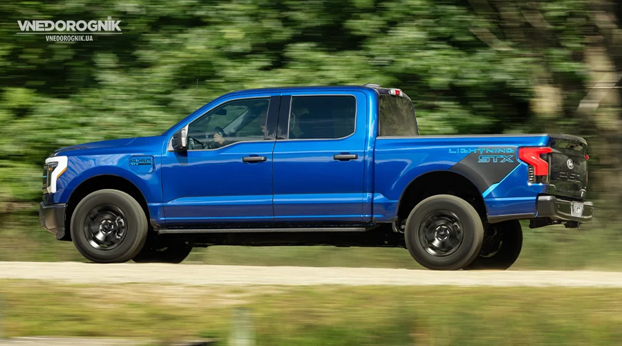 Новый электрический пикап F-150 Lightning STX, демонстрирующий свой дизайн на лесной дороге.
