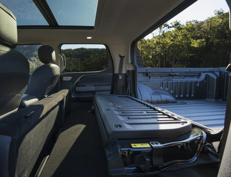 Система Smart Hatch у MG U9: наскрізний багажник. Інтер'єр пікапа MG U9 зі складеними задніми сидіннями та відкритою перегородкою Smart Hatch для перевезення довгомірних вантажів.